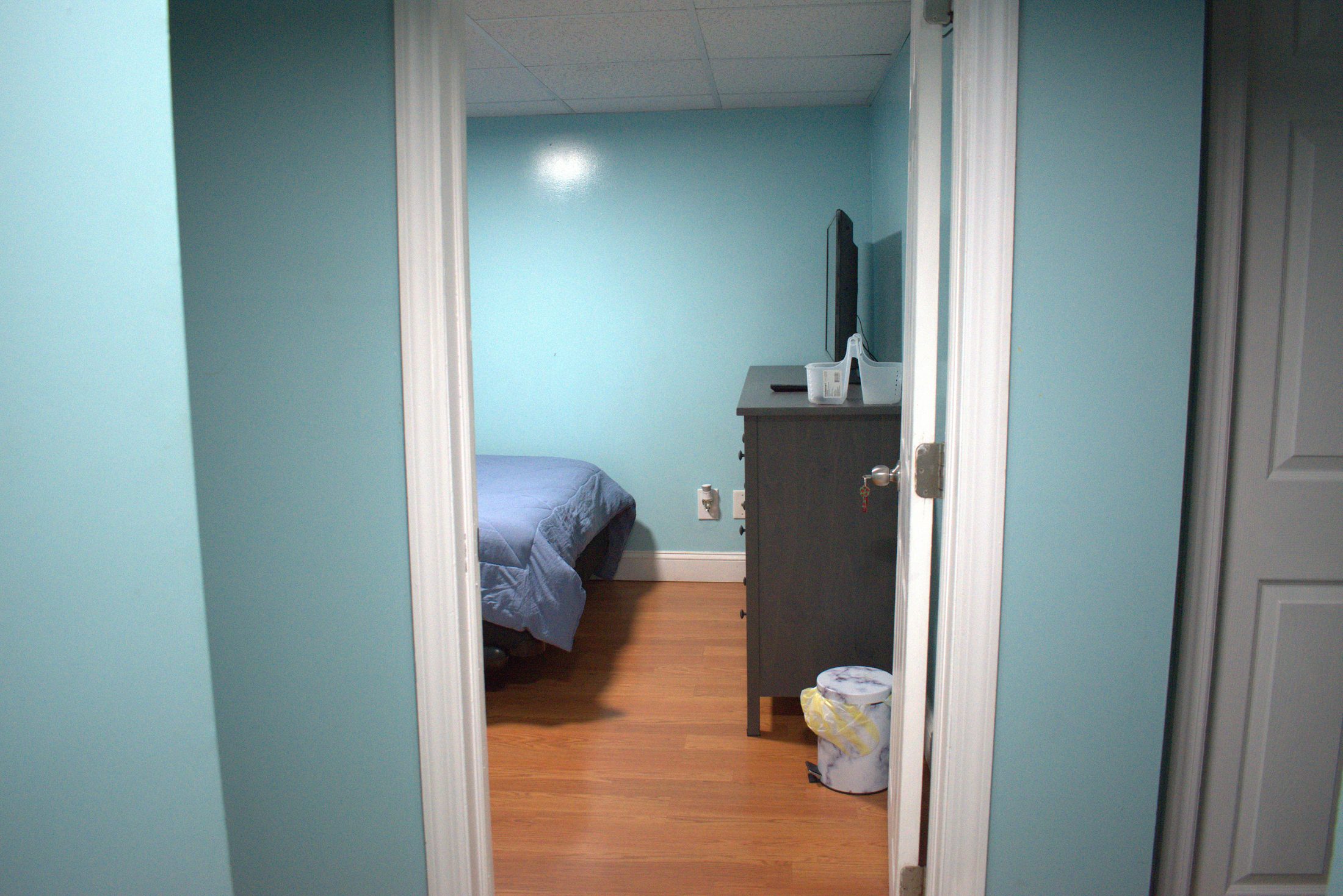 Large Room in the basement apartment with a full bed, dresser, and TV